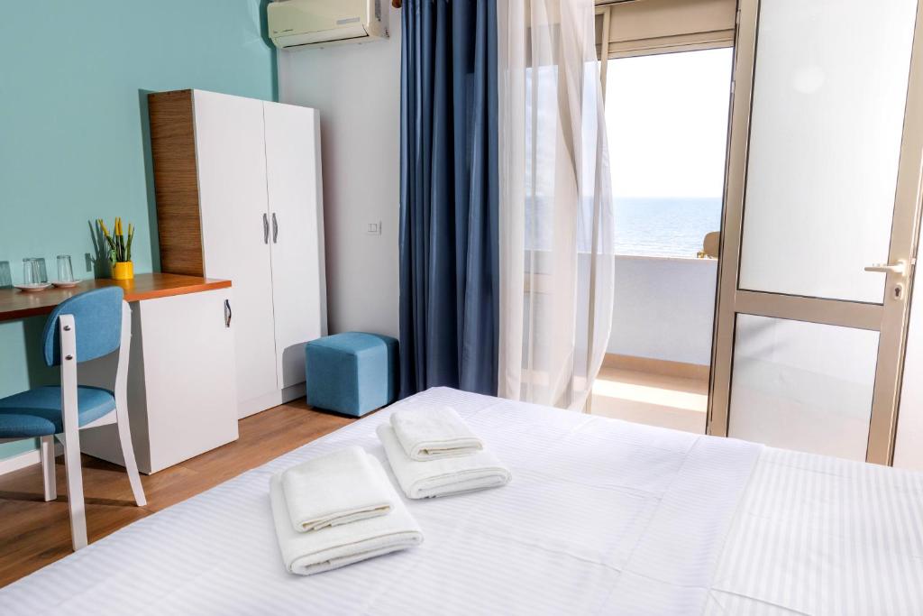 Hotel room with a double bed, a desk and a balcony door opening to a sea view