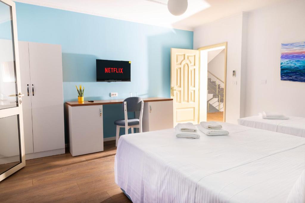 Hotel room with a double bed, a desk and a wall-mounted TV against a light blue wall