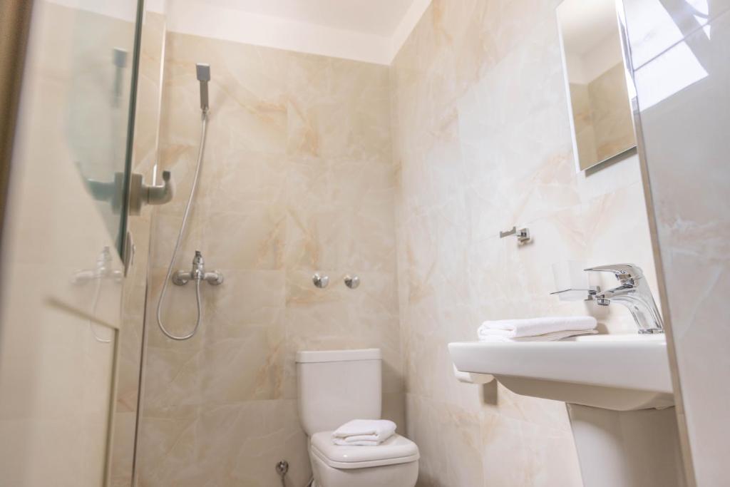 Hotel bathroom with a shower and a washbasin, in cream marble-effect tiles