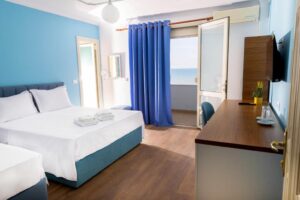 Hotel room with a double bed and a balcony door opening to a sea view